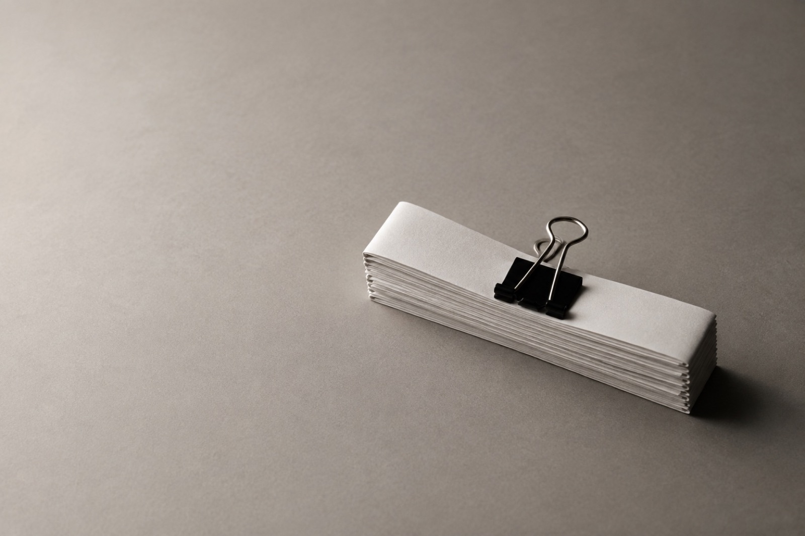 A long paper strip folded into a short stack with a binder clip