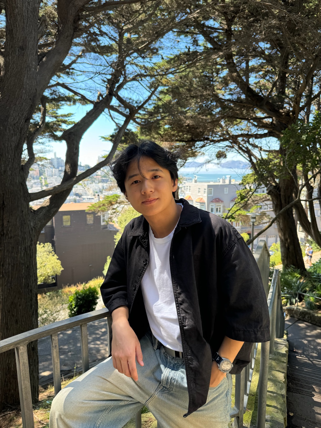 Taiwu Chen in San Francisco, trees and the bay behind him